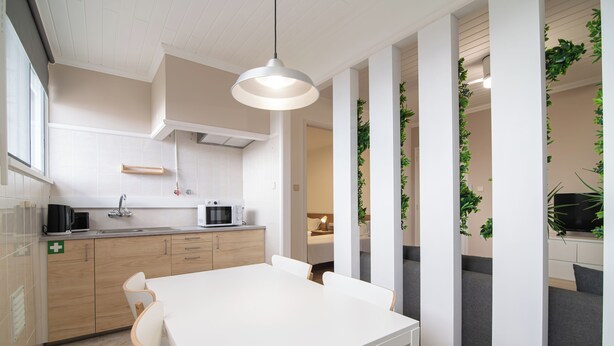 A modern kitchen with a white table and chairs, a microwave, and a sink. - Livramento Residence (Ponta Delgada)
