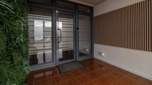 A modern entrance with glass doors, a wooden slat wall, and a green plant wall. - Livramento Residence (Ponta Delgada)