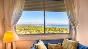 Una habitación con una cama, una lámpara y un ventanal que ofrece vistas a un paisaje con árboles y agua.