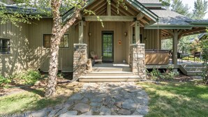 Une maison en bois avec une entrée en pierre, un porche couvert et un chemin en pierre menant à la porte d’entrée.