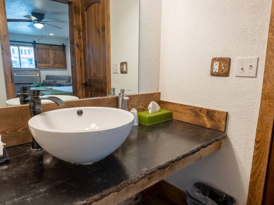 Casa de banho com lavatório suspenso branco, bancada de madeira e espelho.