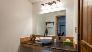 A bathroom with a wooden vanity, a white sink, a mirror, and a towel rack. - Springs Lodge & Cafe (Hot Springs)
