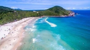 A beach with clear turquoise waters and a sandy shore.
