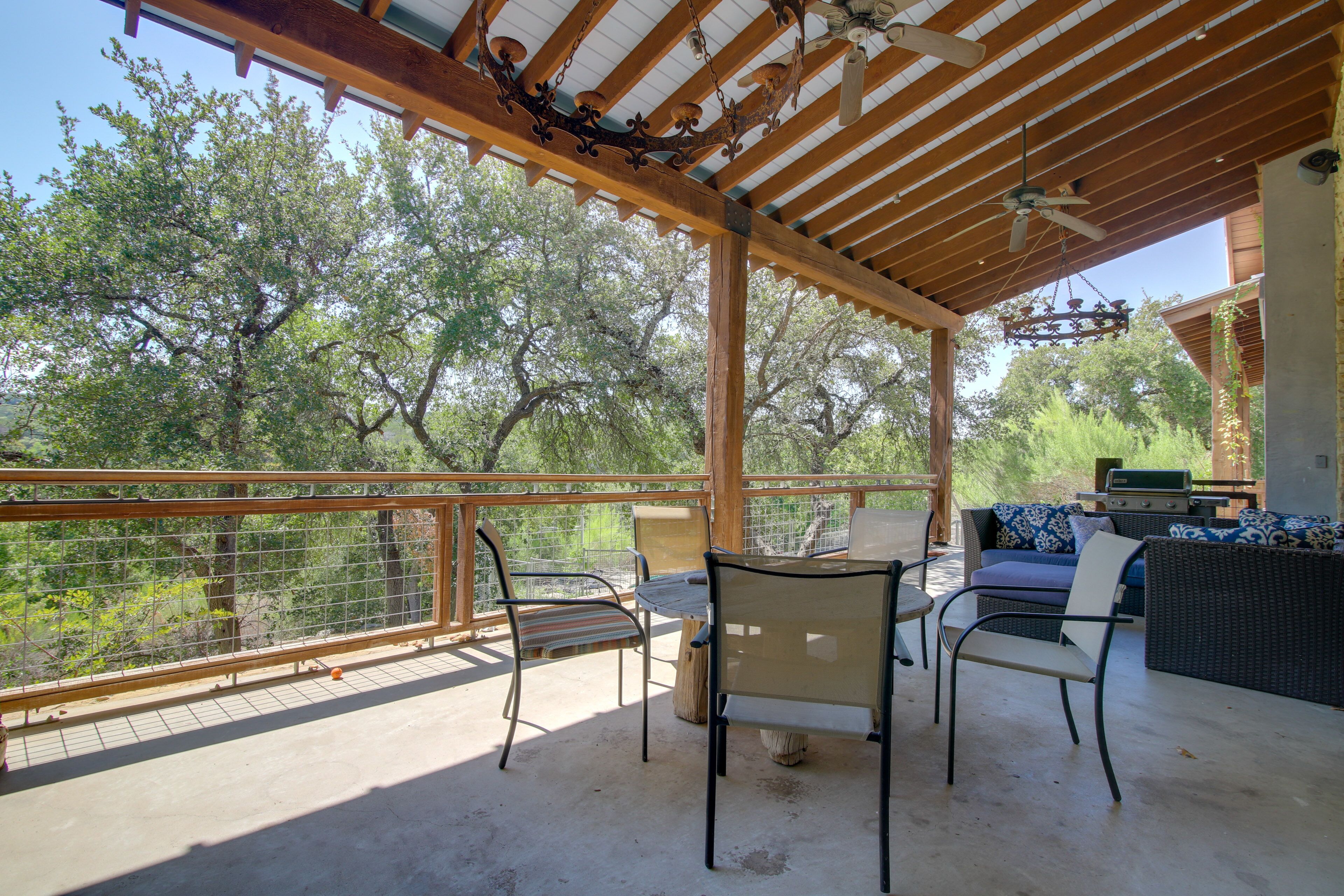 An outdoor patio with a wooden pergola, a dining table with chairs, and a grill area.