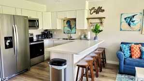 A modern kitchen with a central island, stainless steel appliances, and a coffee-themed decor.