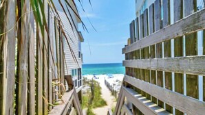 A wooden boardwalk leading to a beach with a clear view of the ocean.