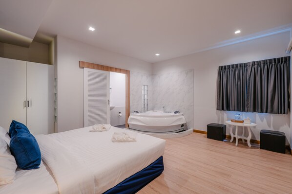 A modern bedroom with a bed, a bathtub, a small table, and a wardrobe. - Blue Rabbit Phuket (Phuket)