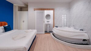 Un dormitorio moderno con una cama grande, un jacuzzi integrado, un armario y un baño con lavabo y espejo.