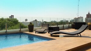 A rooftop pool area with lounge chairs and a view of the city skyline. - Luxurious stay at modern apartment Equipetrol (Santa Cruz de la Sierra)