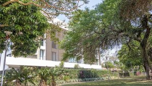 A modern building with a flat roof, surrounded by lush greenery and trees. - Luxurious stay at modern apartment Equipetrol (Santa Cruz de la Sierra)