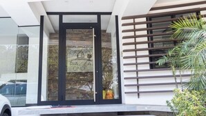 A modern building with a glass entrance, a sign reading "PIAZZA ONCE," and a wooden slatted window on the right. - Luxurious stay at modern apartment Equipetrol (Santa Cruz de la Sierra)