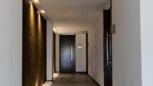 A modern hallway with a textured wall on the left, a dark door at the end, and a light strip along the ceiling. - Luxurious stay at modern apartment Equipetrol (Santa Cruz de la Sierra)