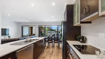 A modern kitchen with a central island, a dining area with chairs, and a large window providing a view of the outdoors.