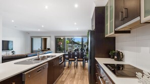 Una cocina moderna con una isla central, un comedor con sillas y un amplio ventanal que ofrece vistas al exterior.