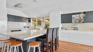 Une cuisine moderne dotée d’un îlot central, de tabourets de bar et offrant une vue sur l’extérieur.