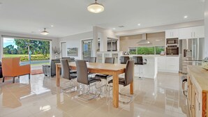Une cuisine moderne avec des meubles blancs, des appareils en acier inoxydable et un coin repas comprenant une table et des chaises en bois.