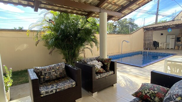Un espacio de estar al aire libre cubierto con mobiliario de mimbre y una piscina.