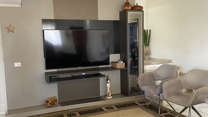 Una sala de estar con un televisor de pantalla plana, un sofá y una mesita de centro.
