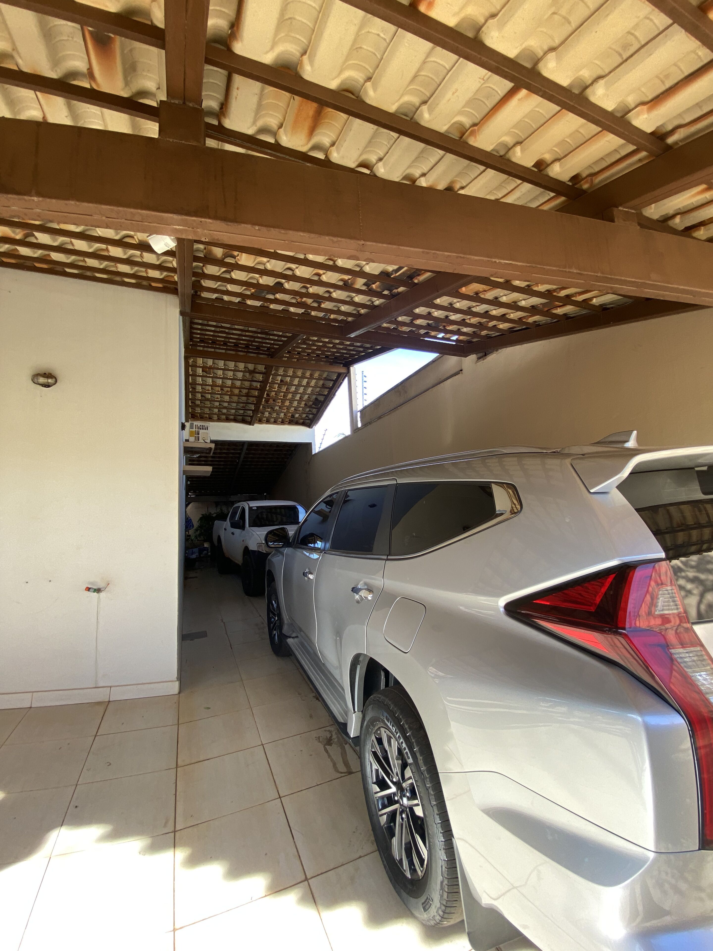 A car garage with a covered roof and tiled floor.
