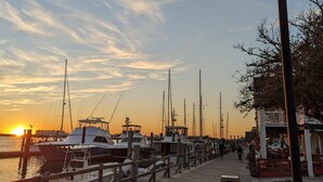 A wooden pier with boats docked, a lamp post, and a sunset in the background. - Coastal Cottage, walk to downtown Beaufort, close to beaches, pet friendly. (Beaufort)