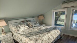 A bedroom with a bed, nightstands, a lamp, and a window. - Coastal Cottage, walk to downtown Beaufort, close to beaches, pet friendly. (Beaufort)