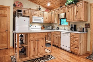 Une cuisine avec des meubles en bois, un réfrigérateur blanc, un four à micro-ondes, une cuisinière, un lave-vaisselle et un évier.