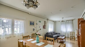 Un vaste espace de vie comprenant une table à manger en bois, un canapé et un lustre.