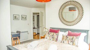 A bedroom with a bed, a desk, a chair, a radiator, a mirror, and a door leading to another room. - 2 Double bedroom Apt in Central Bath with parking

 (Bath)