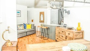A compact living space with a sofa, a dining table, a kitchen area, and a wooden cabinet. - 2 Double bedroom Apt in Central Bath with parking

 (Bath)