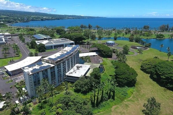 Ein Hotel mit gebogenem Gebäude, einem Parkplatz und Blick auf See und Meer.