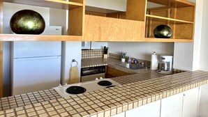A kitchen with wooden shelves, a tiled backsplash, a stove, and a microwave. - Incredible View in Hilo - Pool, A/C, #708 (Hilo)
