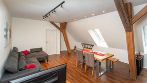 A modern loft apartment with a dining area, a sofa set, and a TV.
