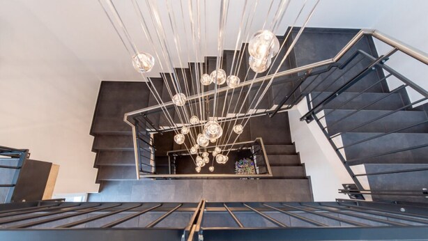 A modern staircase with a unique chandelier design.