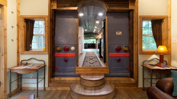 A wooden interior with a central staircase, a table with a lamp, and a leather sofa. - Bluebird Nest (San Marcos)