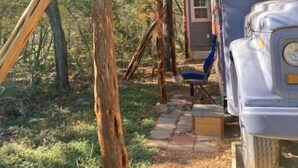 A rustic cabin with a wooden porch and a blue truck parked outside. - Bluebird Nest (San Marcos)