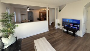 Un salon moderne avec un téléviseur à écran plat, une table basse en bois et un canapé en cuir noir.