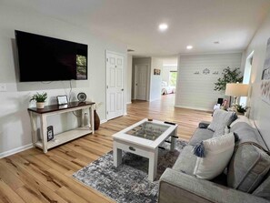 A living room with a flat-screen TV, a foosball table, a sofa, and a coffee table.