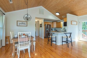 A spacious kitchen with wooden flooring, a central island, and a chandelier.
