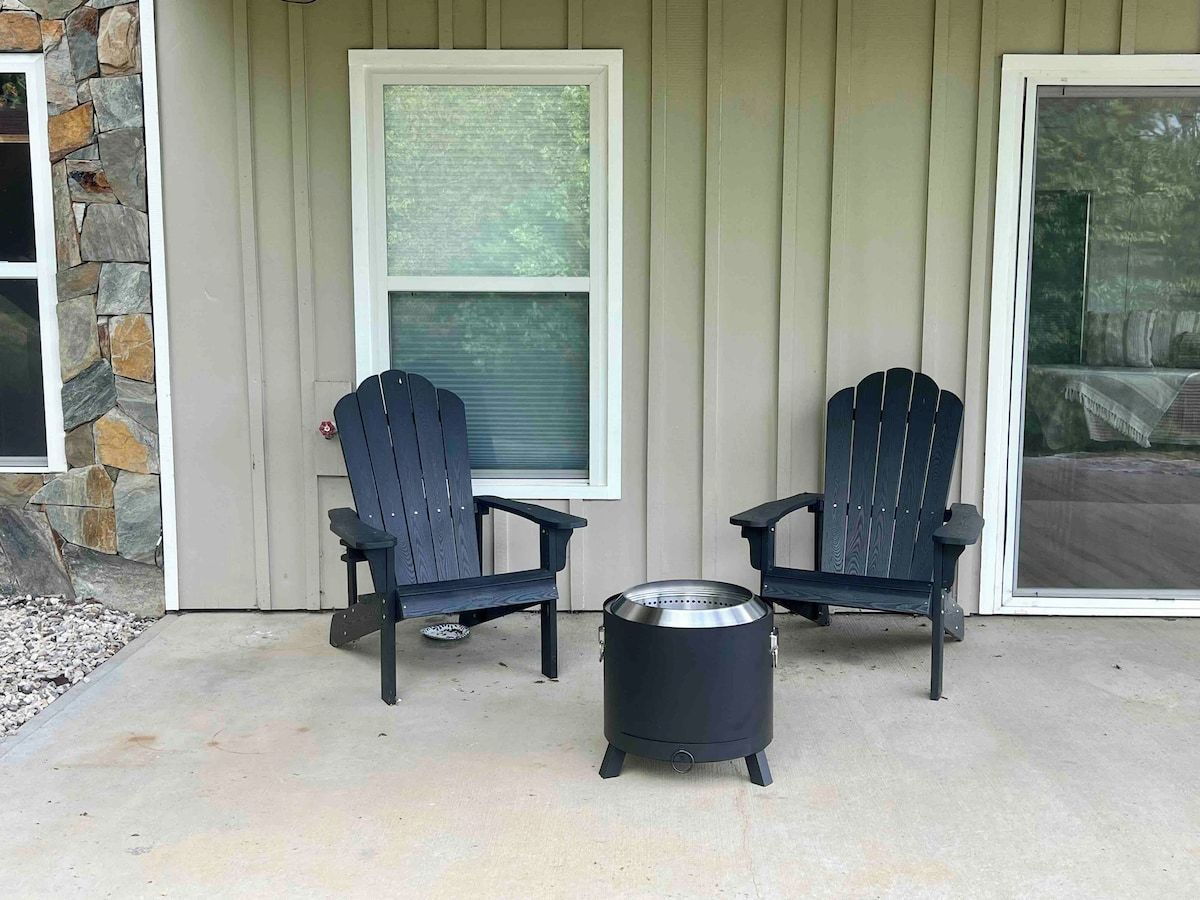 Une terrasse avec deux fauteuils Adirondack et un réchaud portable.