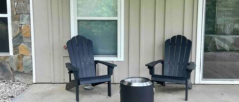 Une terrasse avec deux fauteuils Adirondack et un réchaud portable.