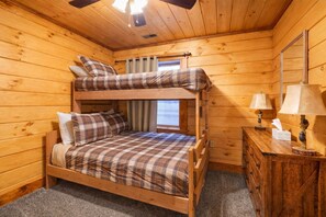 A bunk bed room with a wooden floor, a dresser, two lamps, and a window with curtains. - White Tail Ridge: WALK to Old Man’s Cave + Hot Tub (Logan)
