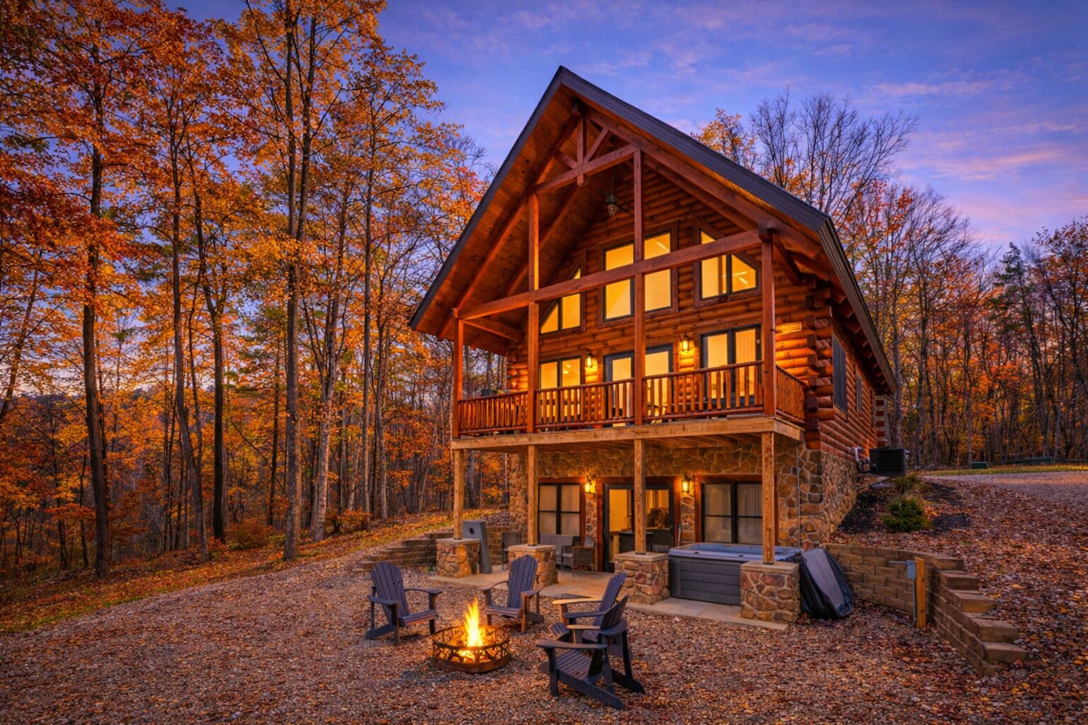 A log cabin with a balcony, a fire pit, and outdoor seating.