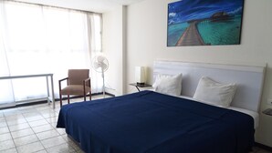 A hotel room with a large bed, a chair, a desk, and a window with curtains. - Hotel Llanito (Aguascalientes)