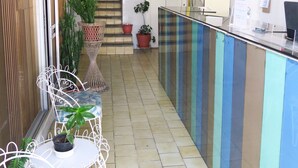 A reception area with a counter, potted plants, a staircase, and a tiled floor. - Hotel Llanito (Aguascalientes)