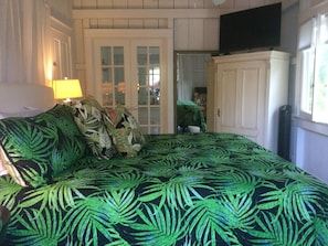 Un dormitorio con una cama, una lámpara, un armario y una puerta que da a otra habitación.