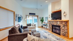 A living room with a fireplace, a sofa set, a television, and a sign that reads "Welcome to the Lake House." - Lake Minocqua Condo w/ Shared Fire Pit! (Minocqua)