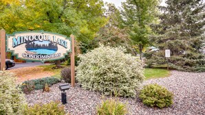 A sign for Minocqua Lake Condominiums surrounded by landscaped gardens and trees. - Lake Minocqua Condo w/ Shared Fire Pit! (Minocqua)