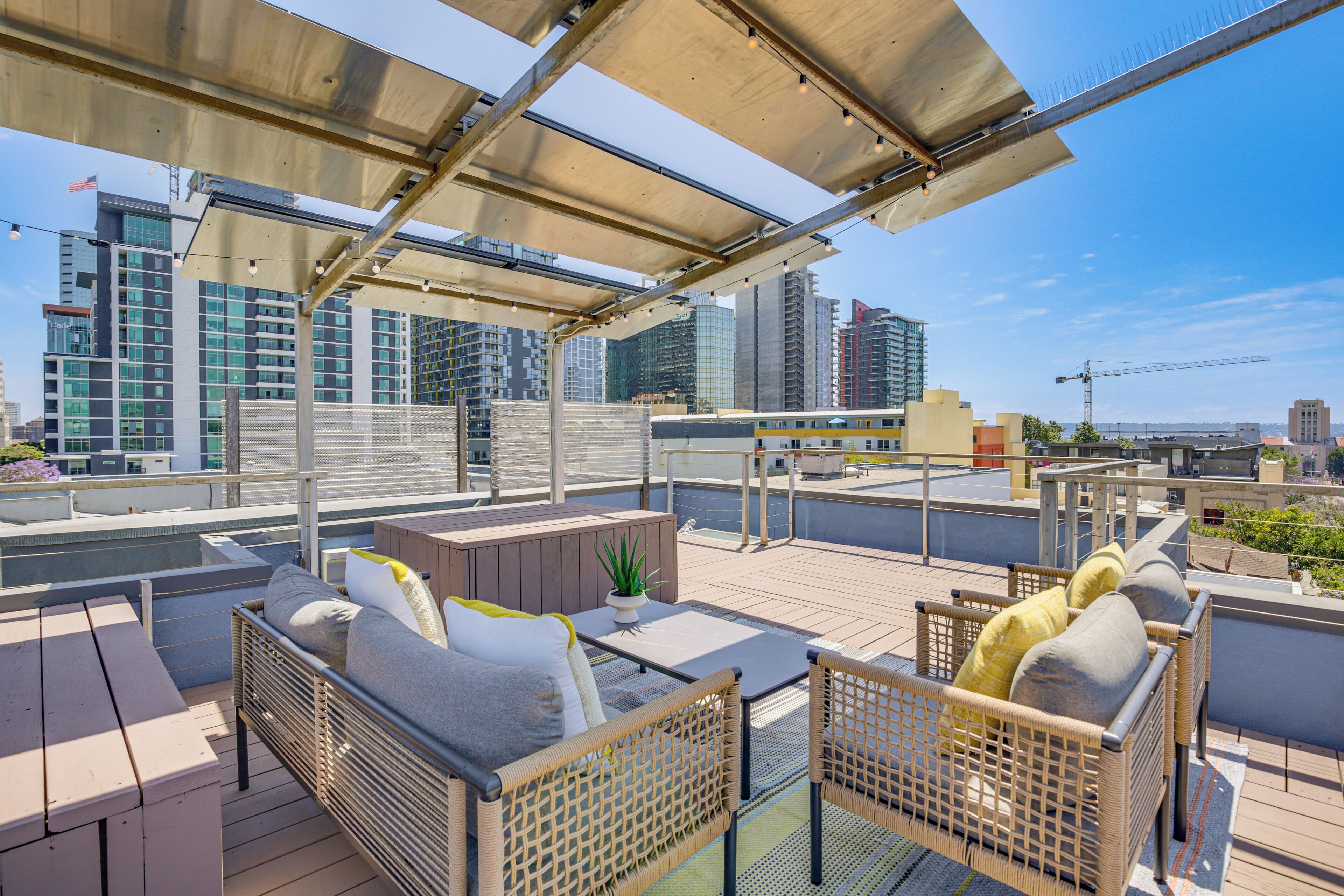 Een dakterras met buitenmeubilair, een zwembad en uitzicht op de skyline van de stad.