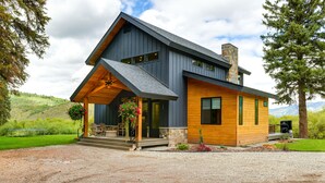A modern two-story house with a covered porch, stone chimney, and a gravel driveway. - Modern Turnerville Cabin w/ Hot Tub & Scenic Views (Turnerville)
