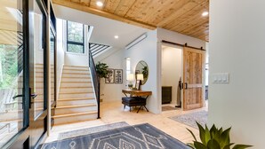 A modern interior with a staircase, wooden flooring, and a large mirror. - Modern Turnerville Cabin w/ Hot Tub & Scenic Views (Turnerville)